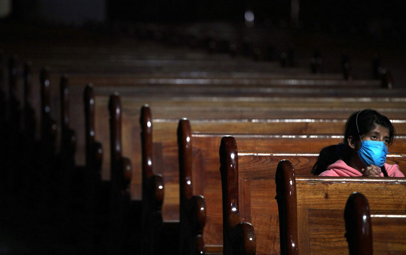 Женщина в маске молится в пустой церкви, фото