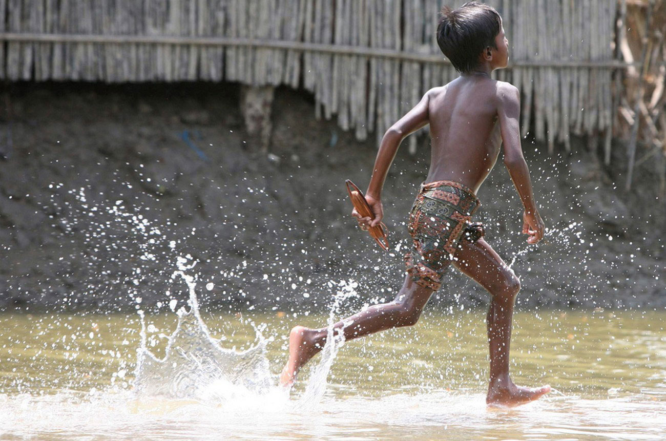ребенок бежит по паводковым водам после урагана в Индии